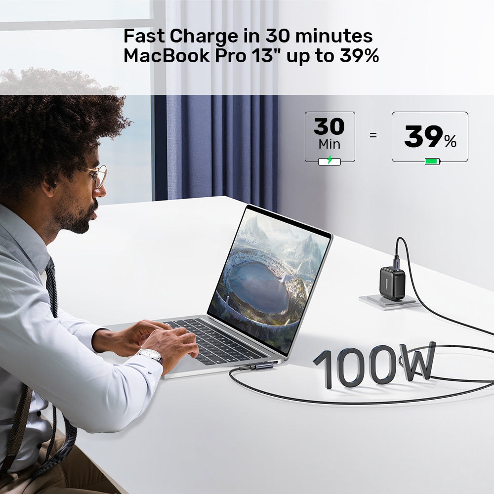 Ein Mann benutzt einen Laptop, der an ein Ladegerät angeschlossen ist. Text zeigt 30 Min. Ladung auf 39%. 100W steht vor dem Ladegerät.