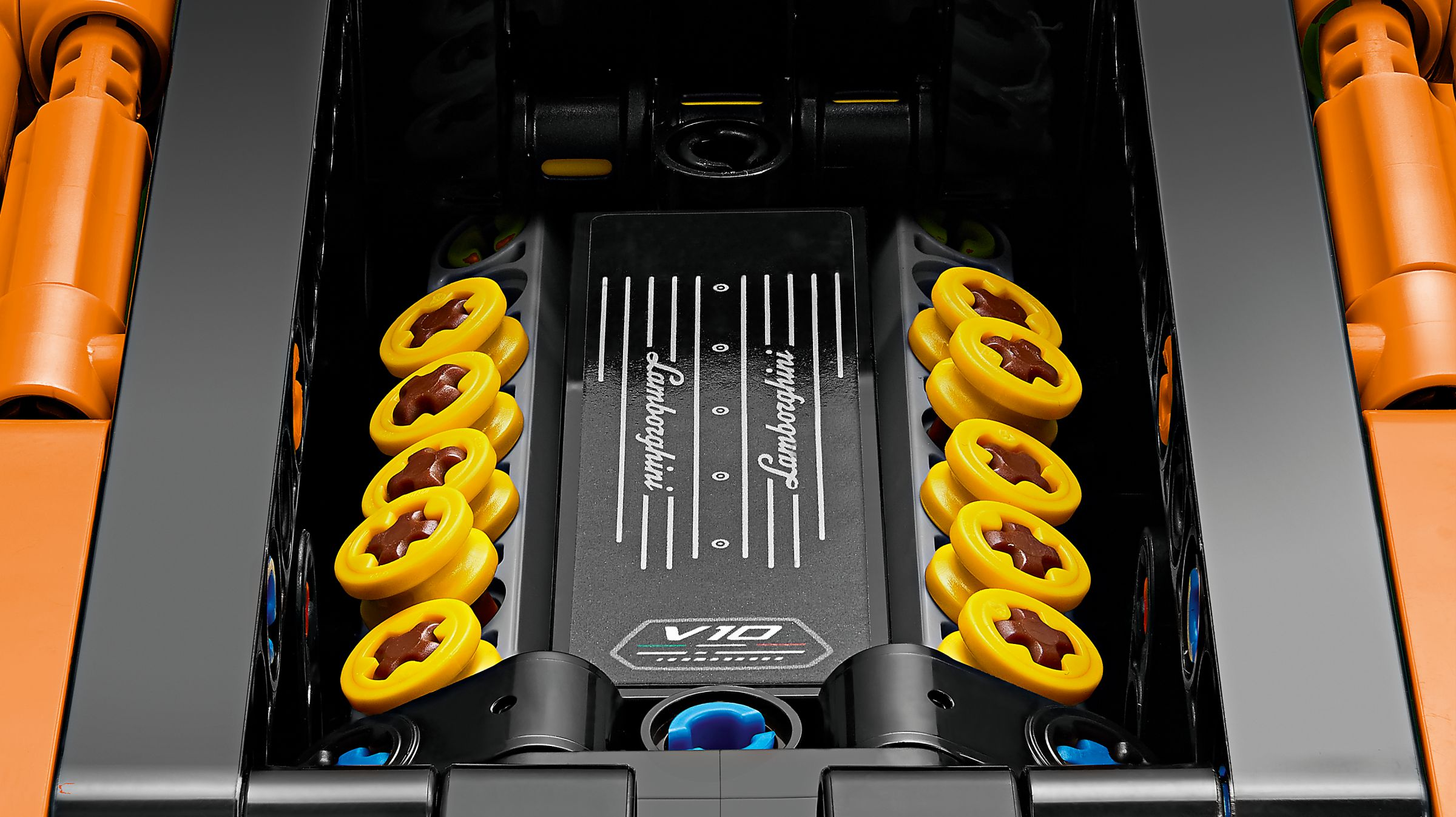 Zbliżenie czarnego modelu silnika Lamborghini. Widoczne są żółte i brązowe detale, a także pomarańczowe i czarne konstrukcje.