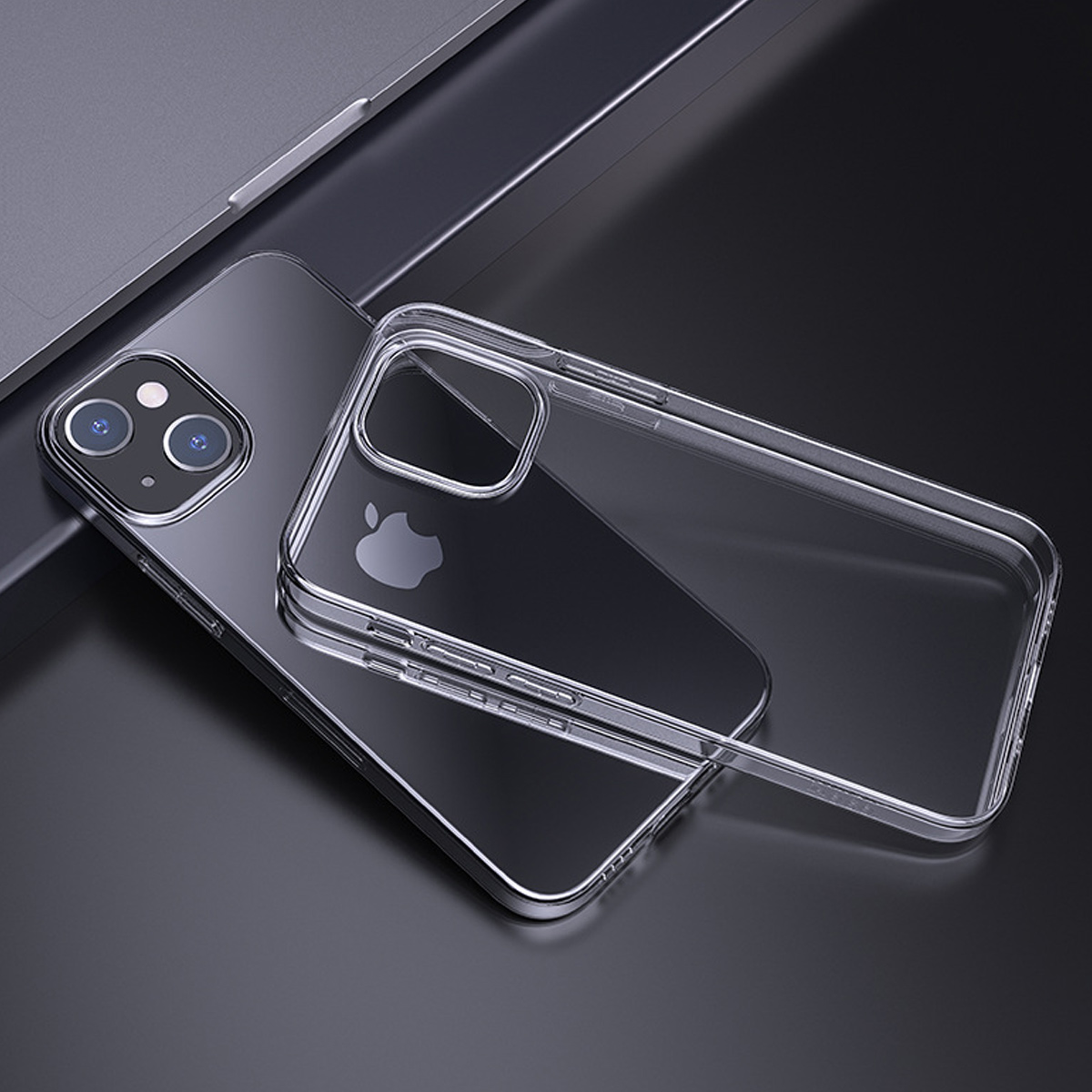 Eine transparente Handyhülle liegt auf einem Telefon neben einem Laptop. Das Telefon hat einen silbernen Rahmen und einen schwarzen Bildschirm.