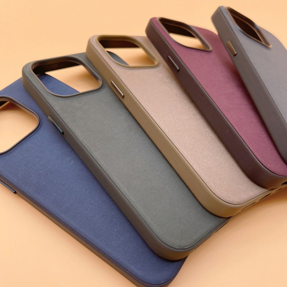 Fünf Handyhüllen in einer Reihe. Farben sind Blau, Grau, Beige, Kastanienbraun und Grau. Sie liegen auf einer hellorangen Oberfläche.