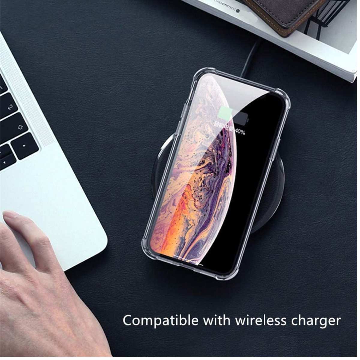 Ein Telefon wird drahtlos auf einer dunklen Oberfläche geladen. Ein Laptop und eine Hand sind sichtbar. Der Bildschirm zeigt ein Ladesymbol.