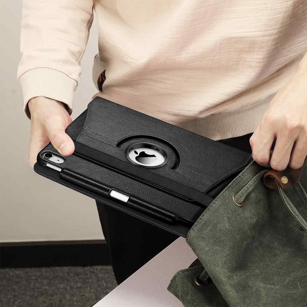 Eine Person hält ein schwarzes Tablet in einer Hülle mit Stift und verstaut es in einer grünen Tasche. Der Hintergrund ist unscharf.