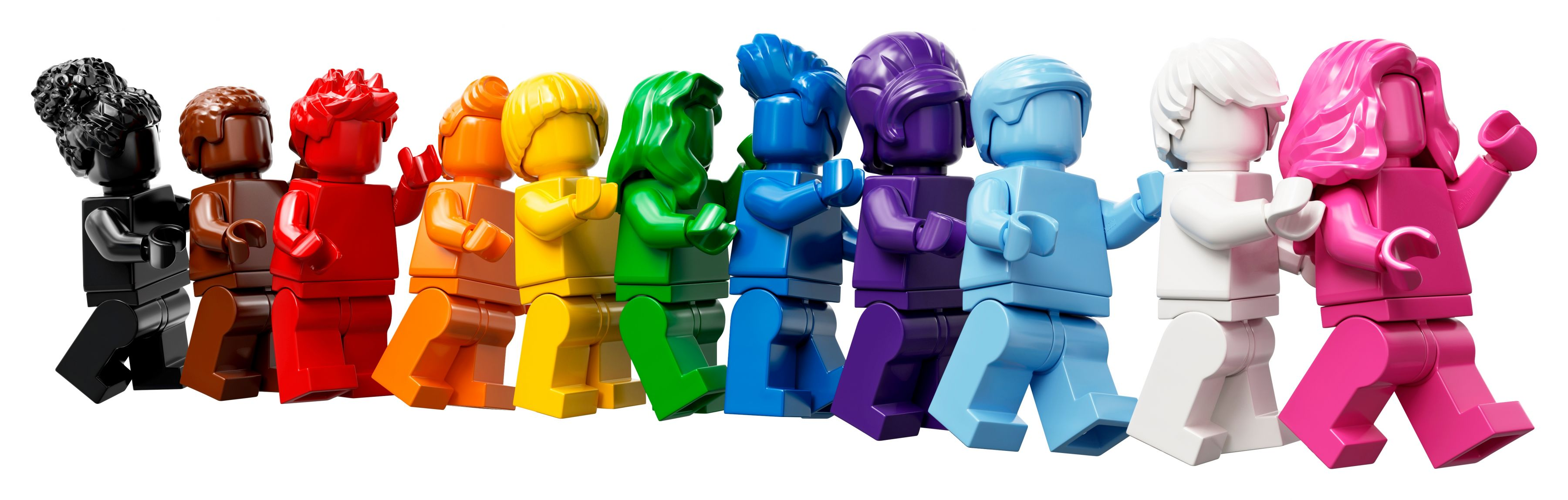 Eine Reihe von Lego-Figuren in verschiedenen Farben, von Schwarz bis Pink, stehen zusammen vor weißem Hintergrund.