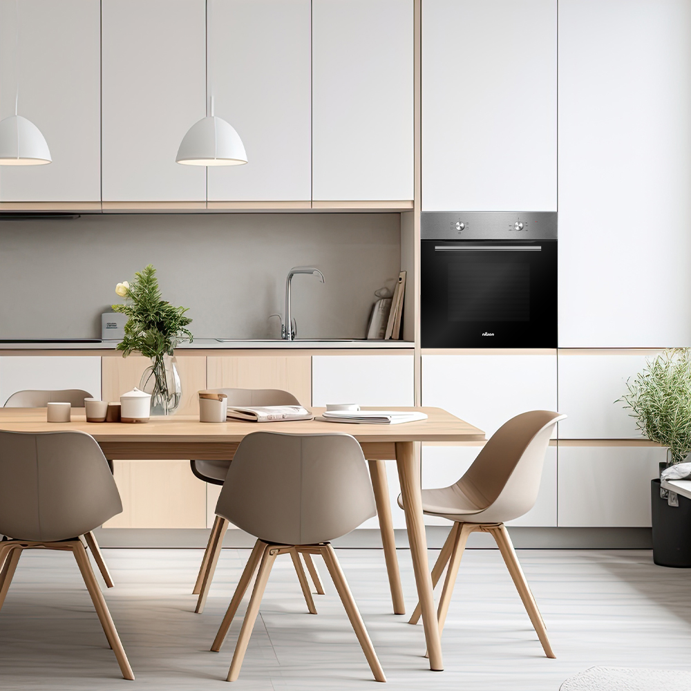 Cocina moderna con armarios blancos, mesa y sillas de madera. Un jarrón con flores está sobre la mesa. Se ve un horno.