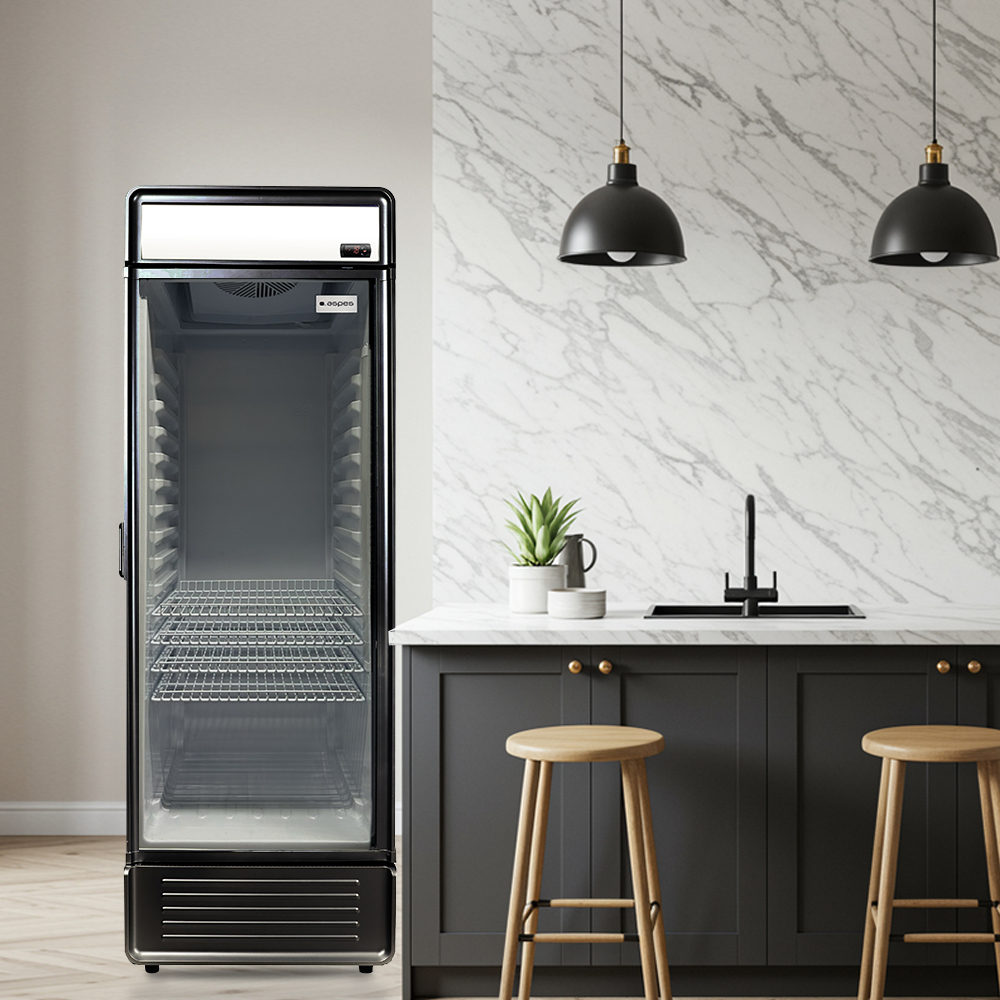 Un refrigerador comercial está junto a una isla de cocina con taburetes. Salpicadero de mármol y lámparas colgantes sobre la isla.