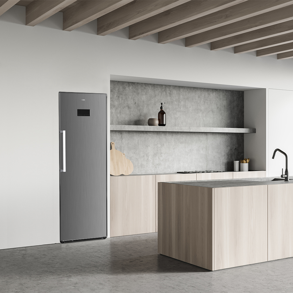 Cocina moderna con nevera gris, armarios de madera y encimera de hormigón. Una tabla de cortar y botellas en una estantería.