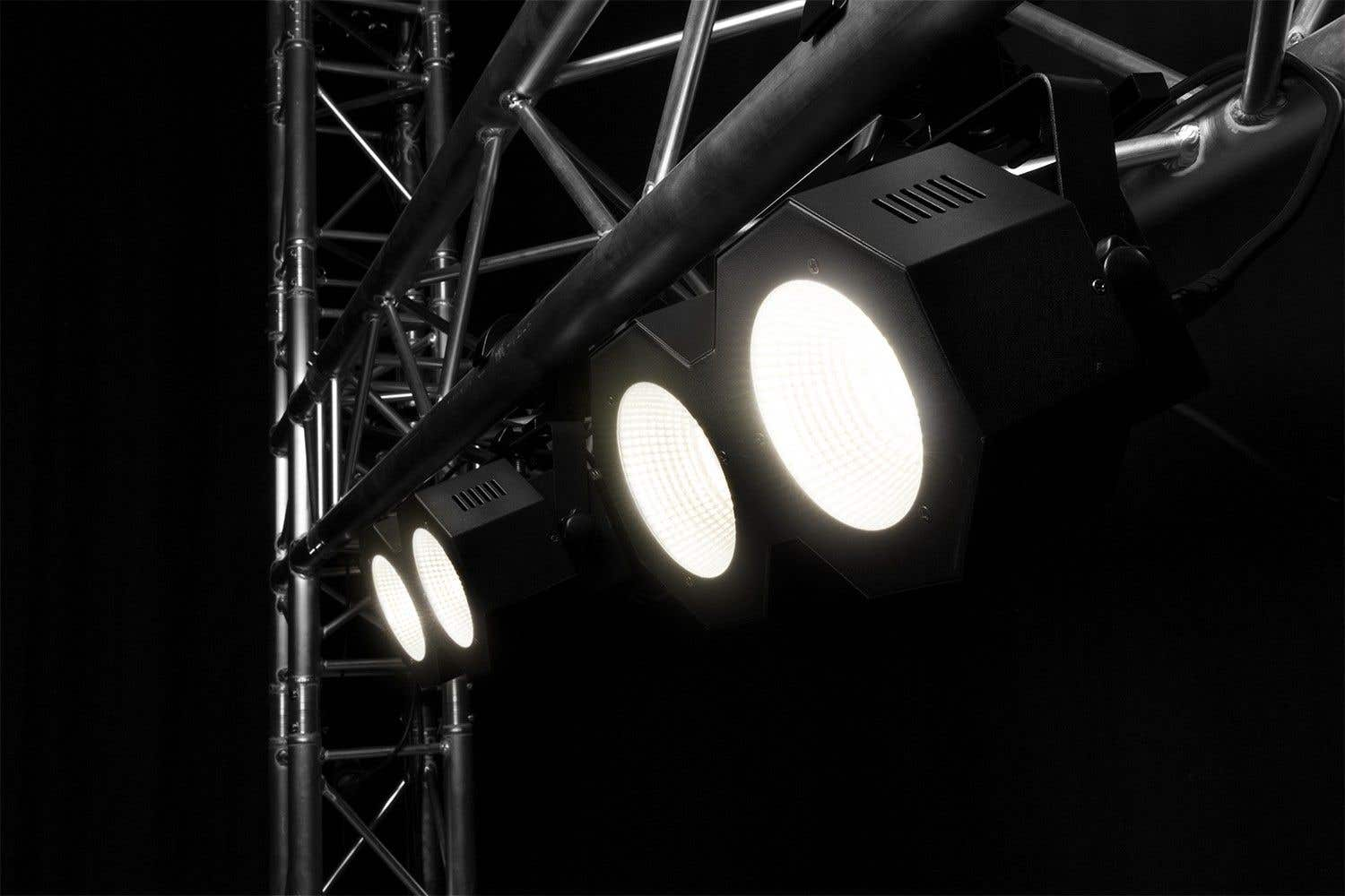 Focos negros con luces blancas brillantes montados en estructura metálica sobre fondo negro.