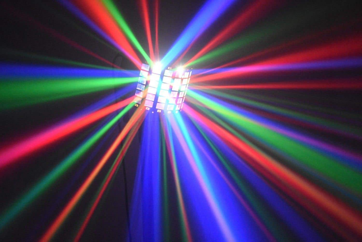 Una luz de escenario proyecta haces de luz roja, verde y azul desde una fuente rectangular central contra un fondo oscuro.