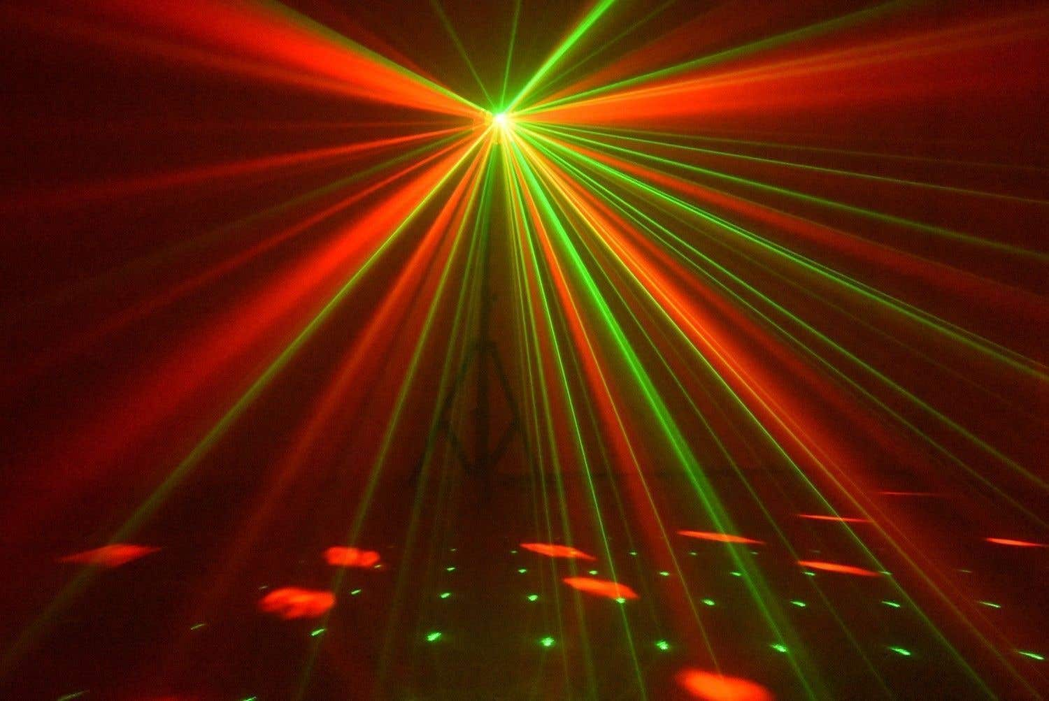 Rayos láser rojos y verdes irradian desde un punto central. El suelo refleja la luz con manchas verdes y rojas dispersas.