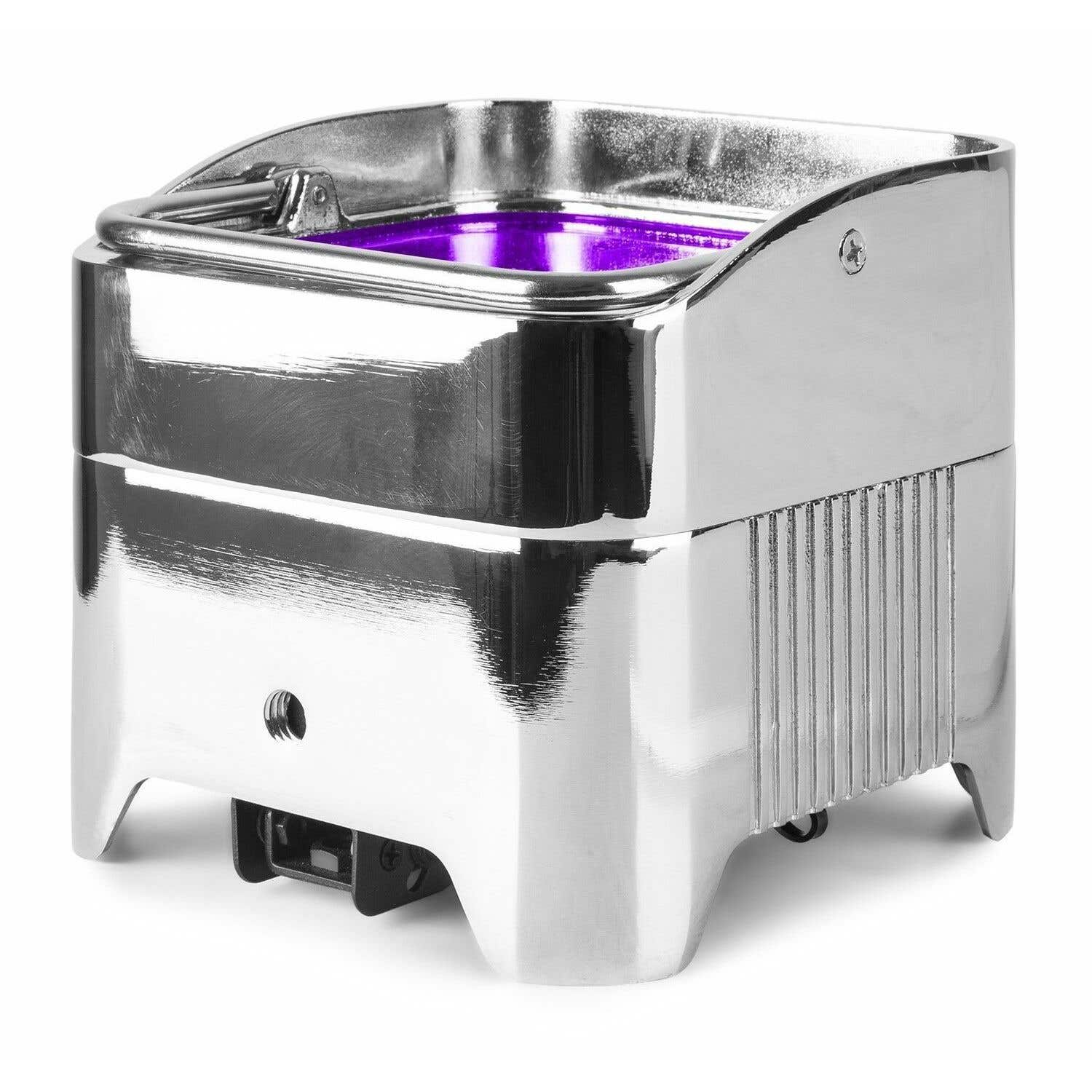 Un electrodoméstico brillante, cromado, con asa e interior morado. Tiene un lado estriado y descansa sobre una superficie blanca.