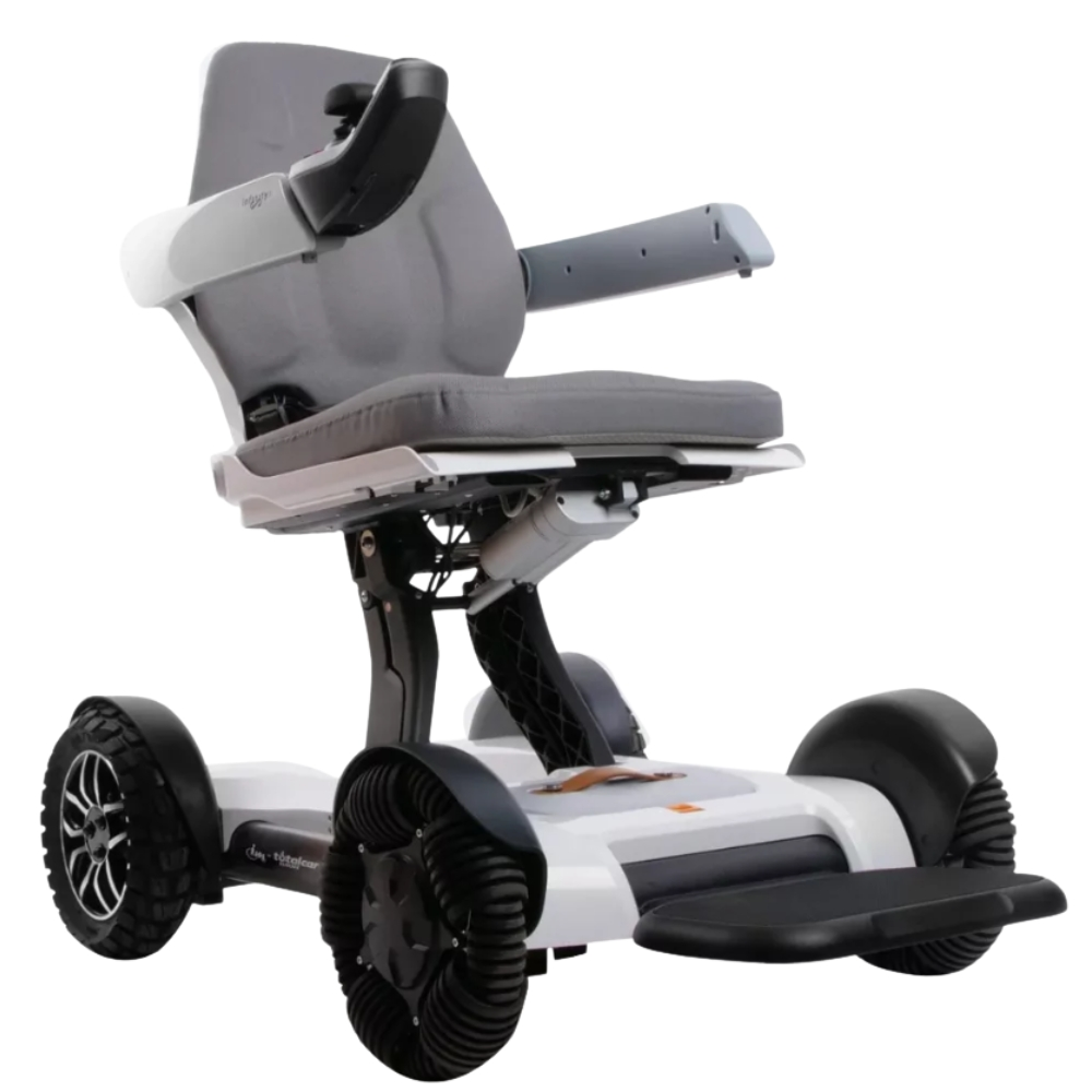 Un scooter de movilidad gris y blanco. Tiene asiento, reposabrazos y reposapiés. Las ruedas son negras y la base es blanca.