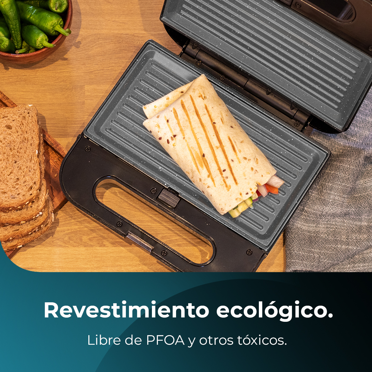 Una piastra per sandwich con un panino avvolto all'interno. Pane e peperoni ai lati. Testo in basso: rivestimento ecologico.