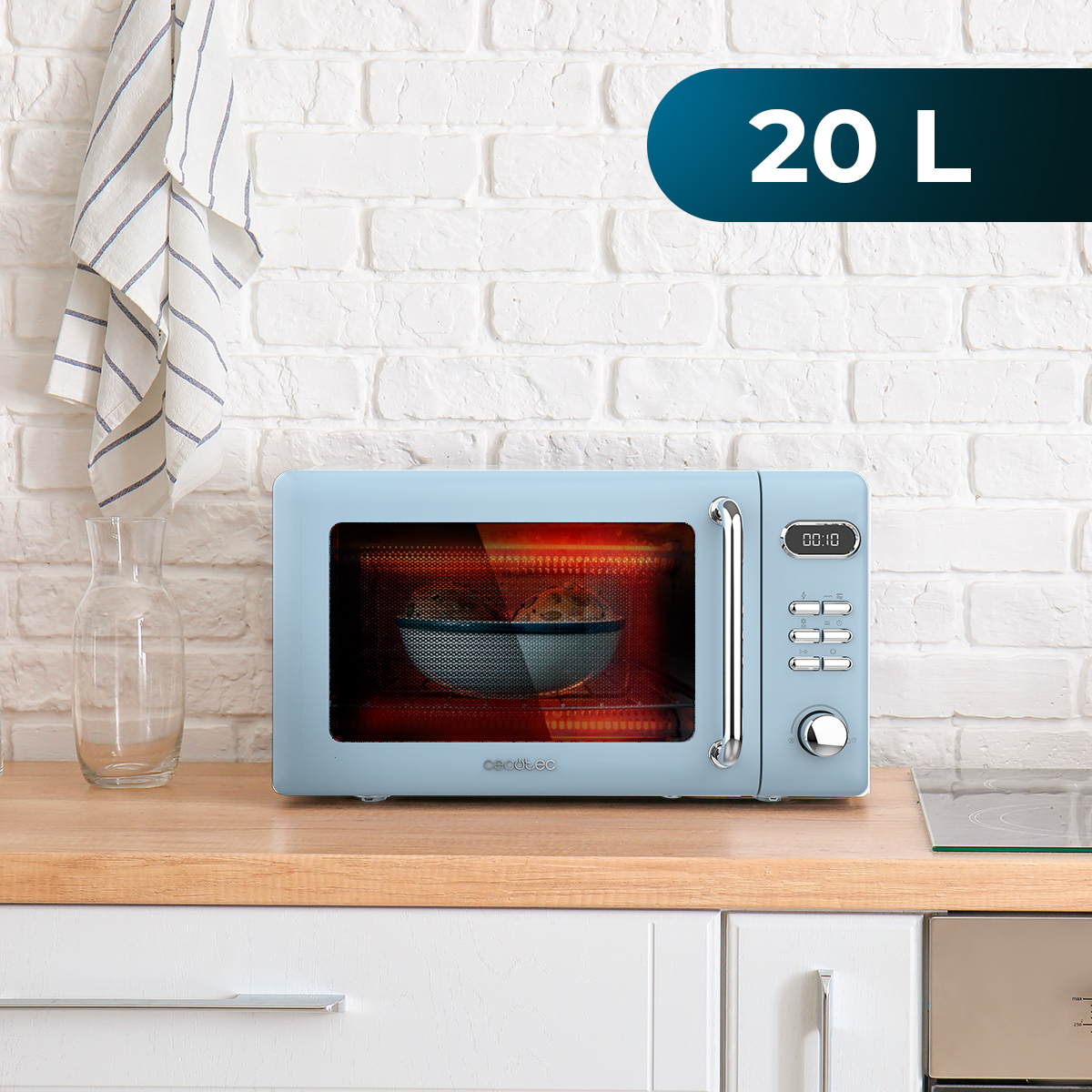 Jasnoniebieska kuchenka mikrofalowa stoi na drewnianym blacie. W środku jest miska. Szklany dzbanek i biała ceglana ściana są w tle.