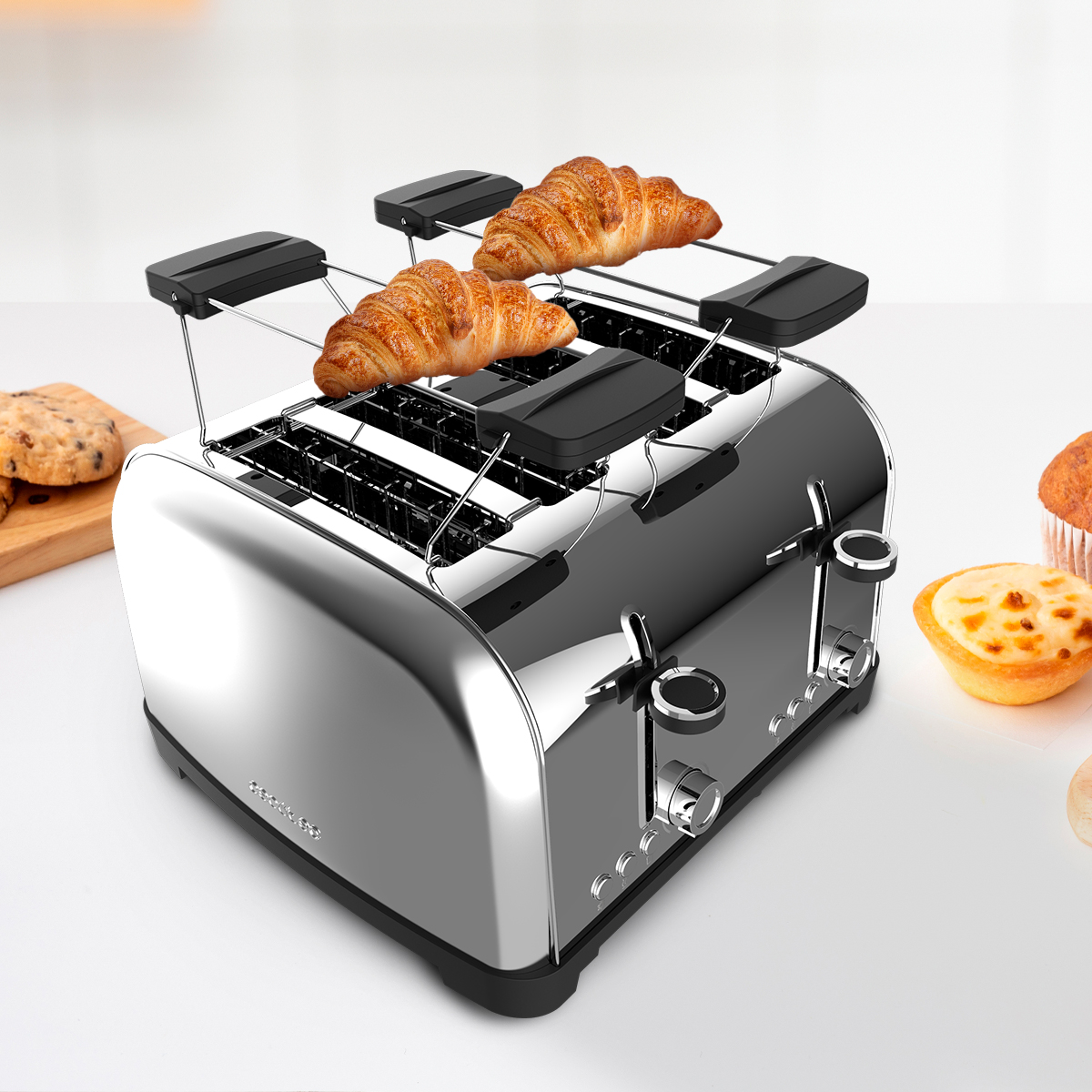 Chromowany toster z dwoma rogalikami na górze. Ciastka i wypieki na białej powierzchni w tle.