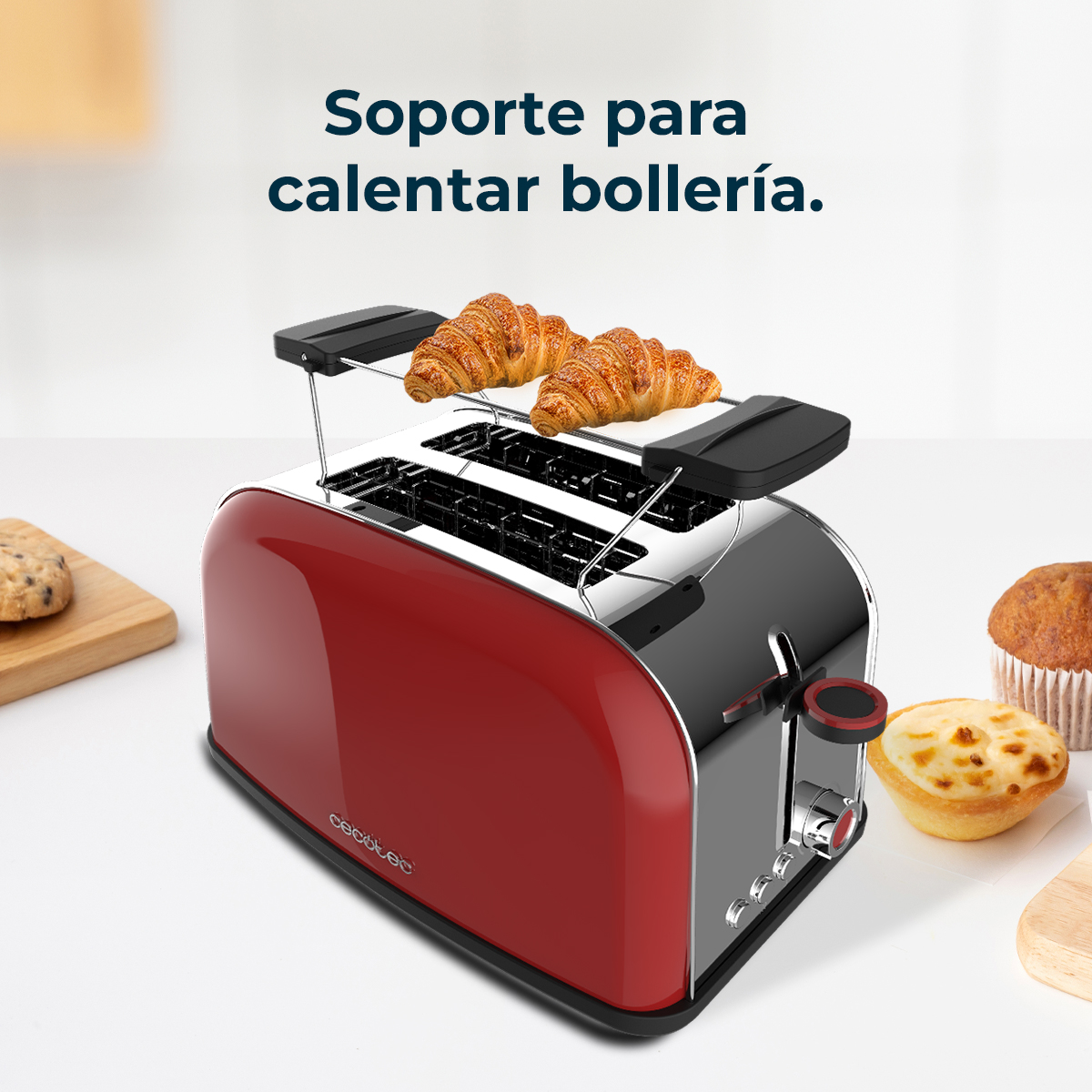 Una tostadora roja y plateada con cruasanes encima y pasteles a un lado, sobre una superficie blanca.