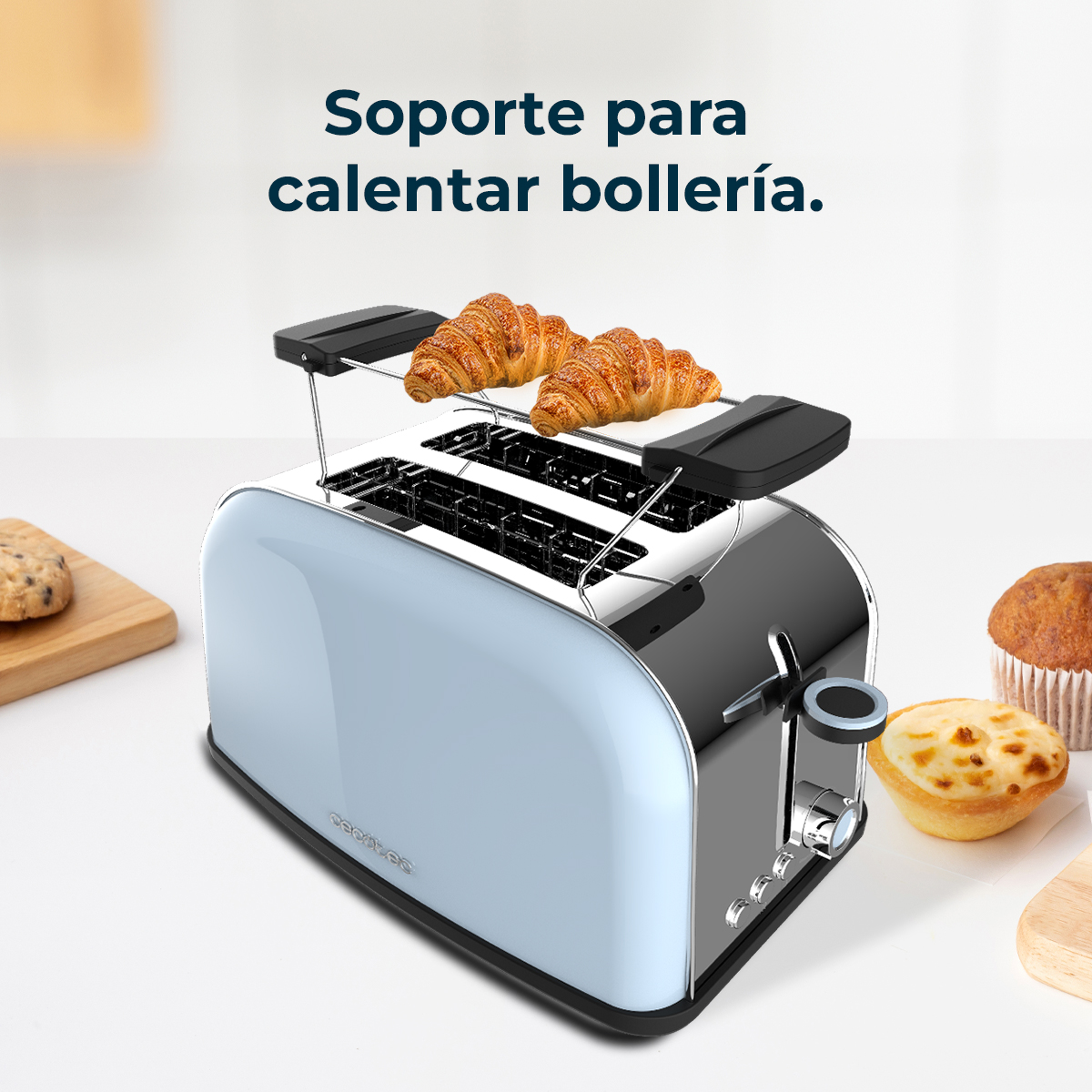 Una tostadora azul y cromada con cruasanes encima. Galletas y magdalenas a los lados.