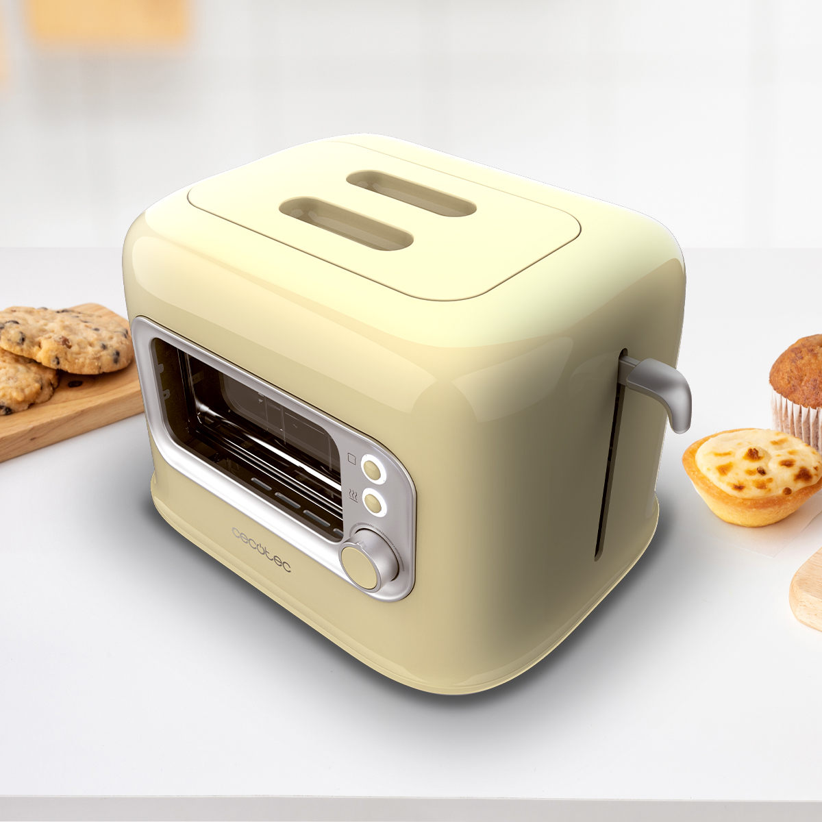 Tostapane color crema con due fessure, un pannello di controllo e una maniglia. Biscotti e un muffin sul tavolo.