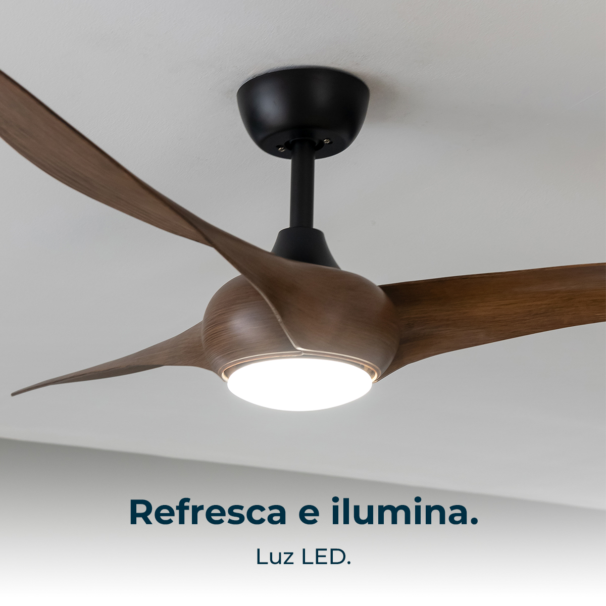 Wentylator sufitowy z drewnianymi łopatkami i centralnym światłem, zamontowany na białym suficie. Tekst: Chłodzi i oświetla. Światło LED.