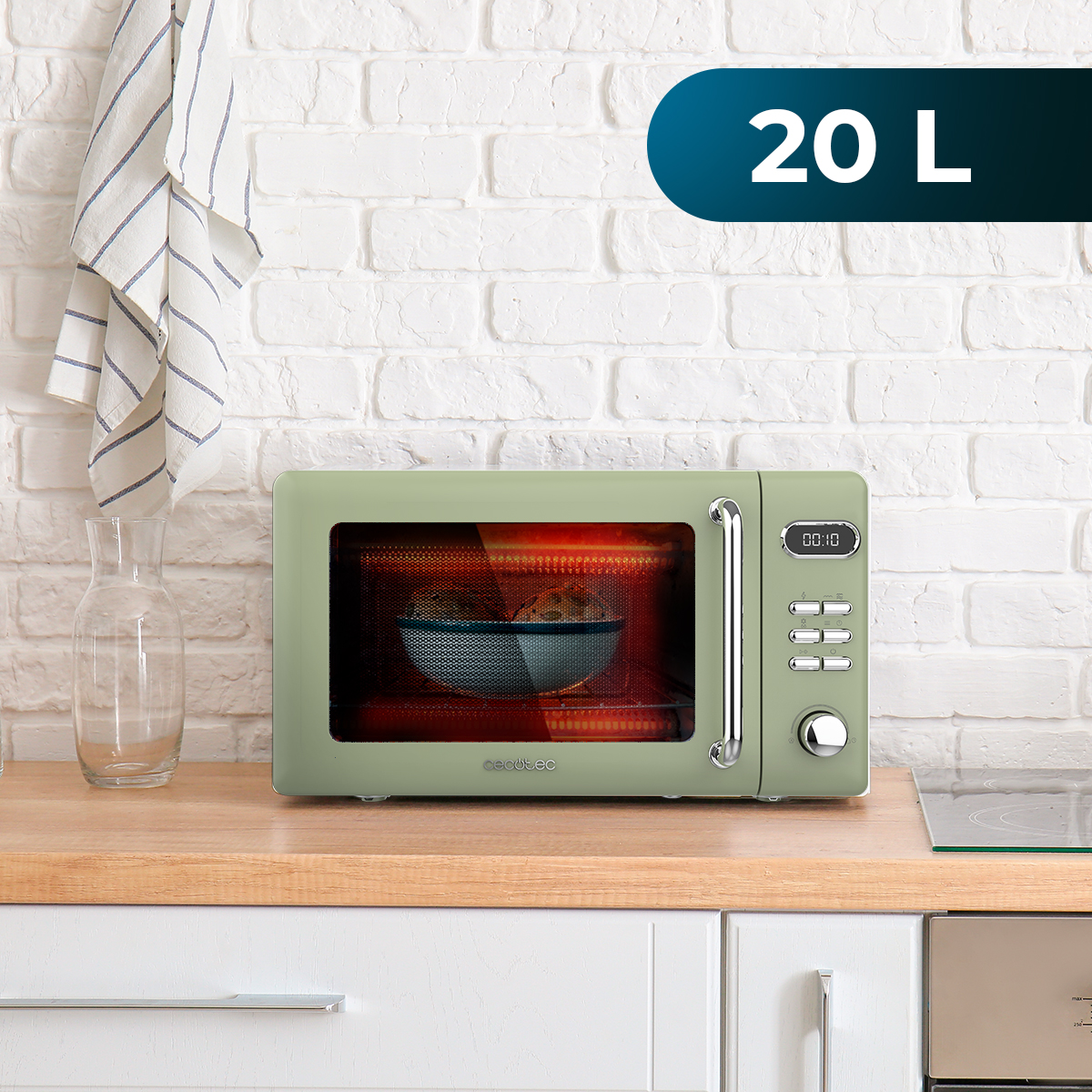 Zielona kuchenka mikrofalowa na drewnianym blacie, z miską w środku. Szklany słoik i pasiasty ręcznik po lewej.