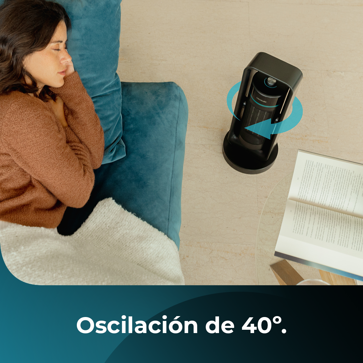 Donna che dorme su un divano verde acqua, coperta da una coperta. Un riscaldatore nero è vicino al divano e un libro aperto è vicino.