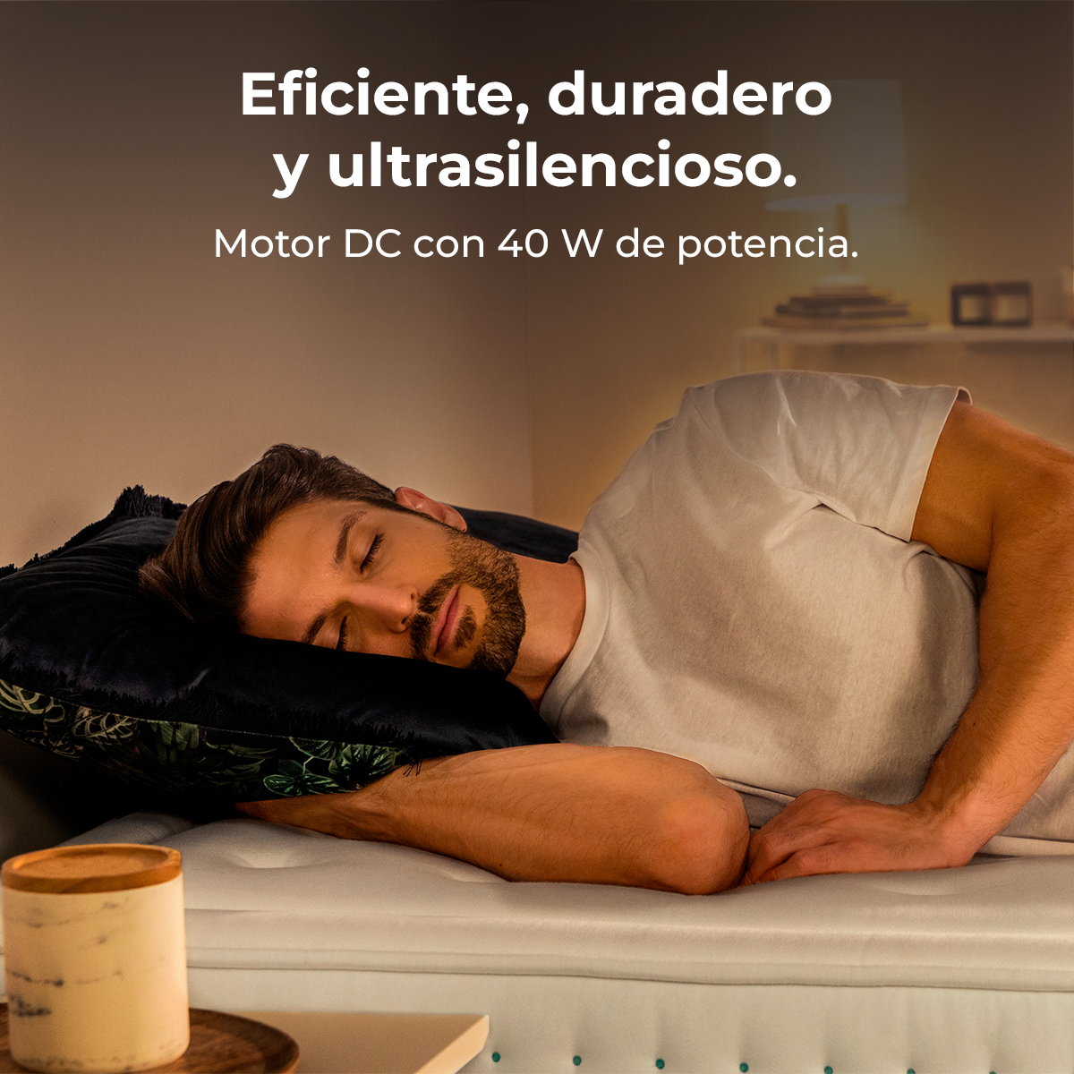Mężczyzna śpi na łóżku z czarną poduszką. Tekst po hiszpańsku powyżej brzmi: 'Wydajny, trwały i ultracichy'.