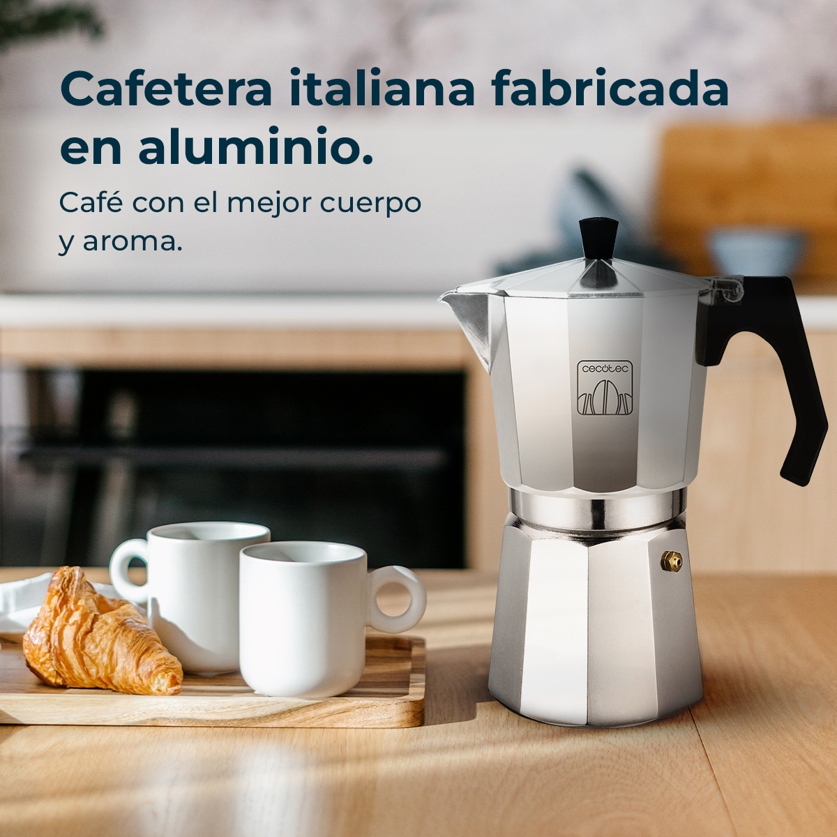 Eine italienische Kaffeemaschine aus Aluminium mit zwei weißen Tassen, einem Croissant und Text. Die Szene ist ein Holztisch mit unscharfem Hintergrund.