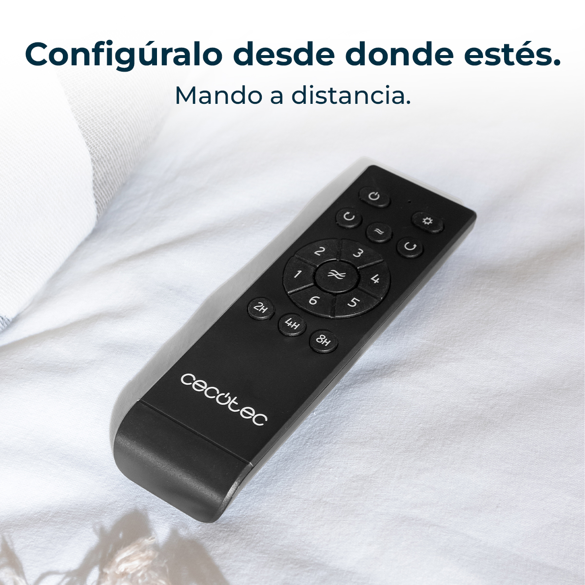Un telecomando nero su un lenzuolo bianco. Il telecomando ha pulsanti con numeri e simboli. Il marchio cecotec è visibile.