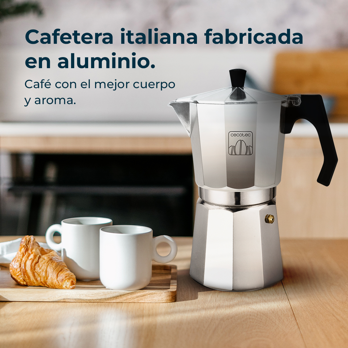 Italienische Kaffeemaschine aus Aluminium, zwei weiße Tassen, Croissant auf einem Holztablett, alles auf Holzuntergrund.