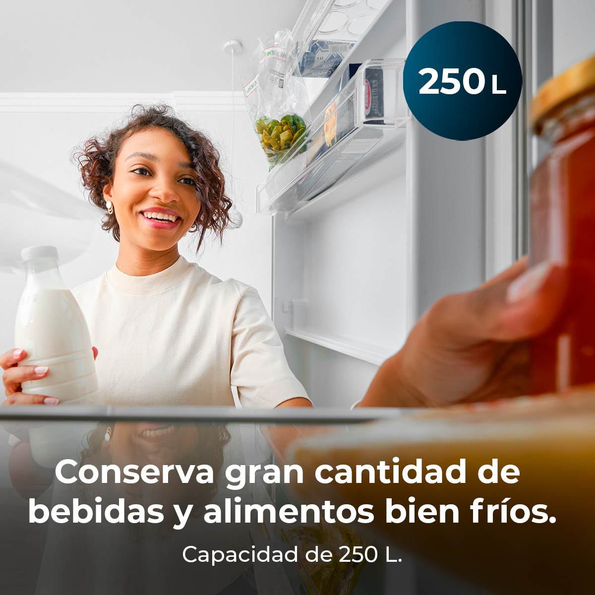 Kobieta uśmiecha się, trzymając mleko. Otwarta lodówka z jedzeniem w środku. Tekst: 'Conserva gran cantidad... 250 L.'