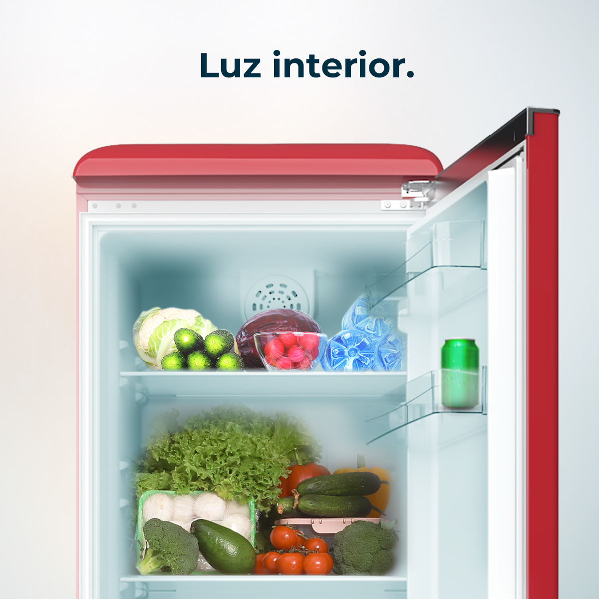 Un refrigerador rojo con la puerta abierta, lleno de verduras, frutas y una lata. El refrigerador está bien iluminado, mostrando su contenido claramente.