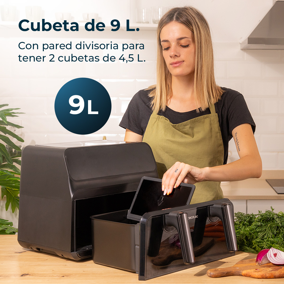 Kobieta z blond włosami, w czarnej koszuli i zielonym fartuchu, trzyma czarną frytkownicę powietrzną o pojemności 9L.