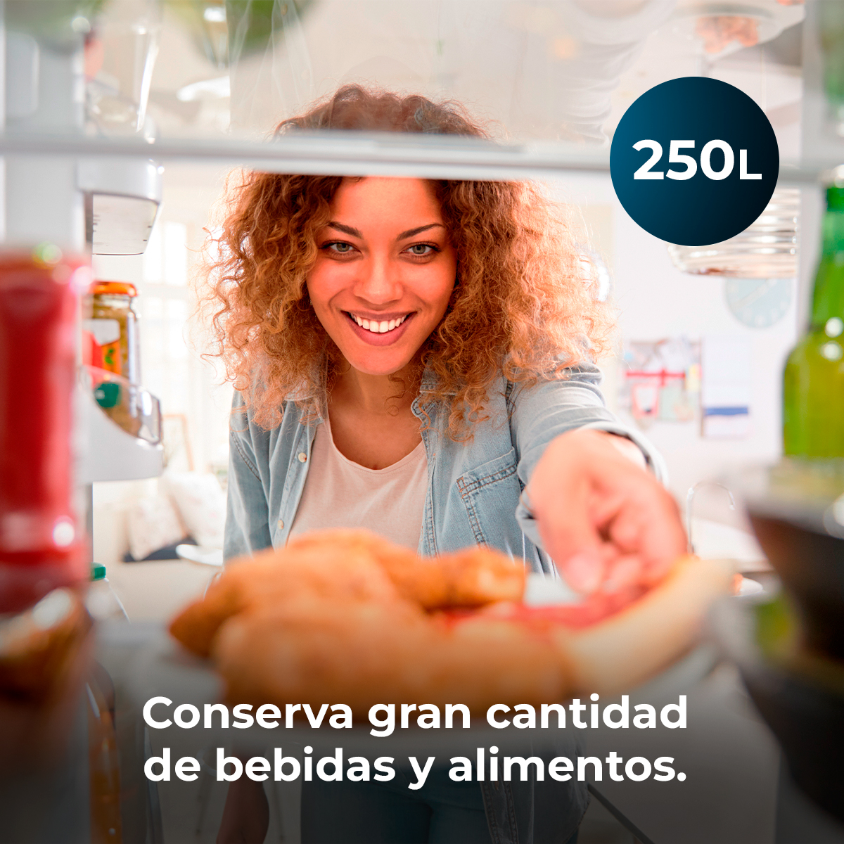 Kobieta uśmiecha się, sięgając po jedzenie do lodówki. Tekst: Przechowuje dużą ilość napojów i jedzenia.