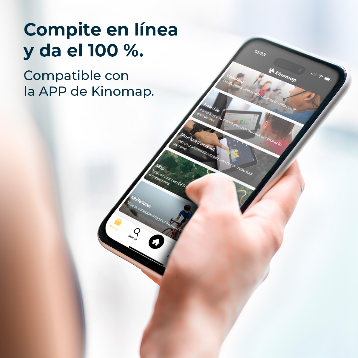 Una mano tiene un telefono con l'app Kinomap. Lo schermo mostra opzioni di allenamento, con testo in spagnolo. Lo sfondo è sfocato.