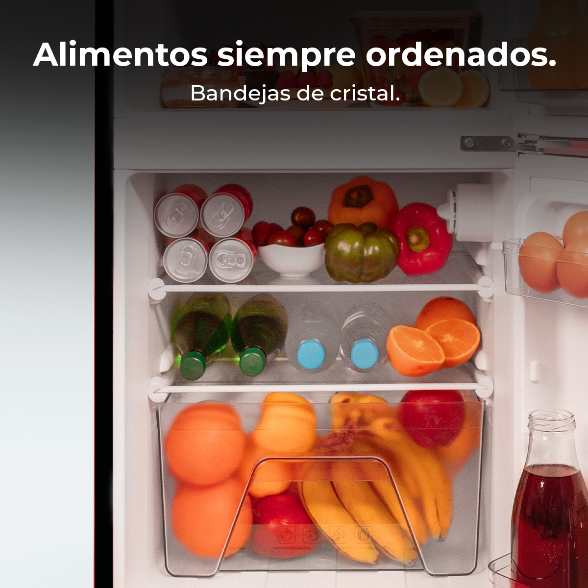 Otwarta lodówka, wypełniona jedzeniem: owoce, warzywa, napoje i jajka. Na górze tekst: 'Zawsze uporządkowana żywność. Kryształowe tace'.