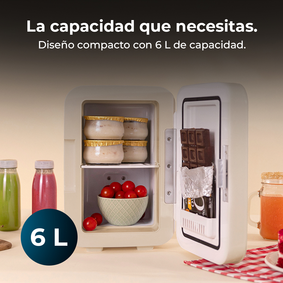 Mini lodówka z otwartymi drzwiami, pokazująca jogurt, pomidory i czekoladę. Napoje w butelkach po lewej stronie. Pojemność to 6L.
