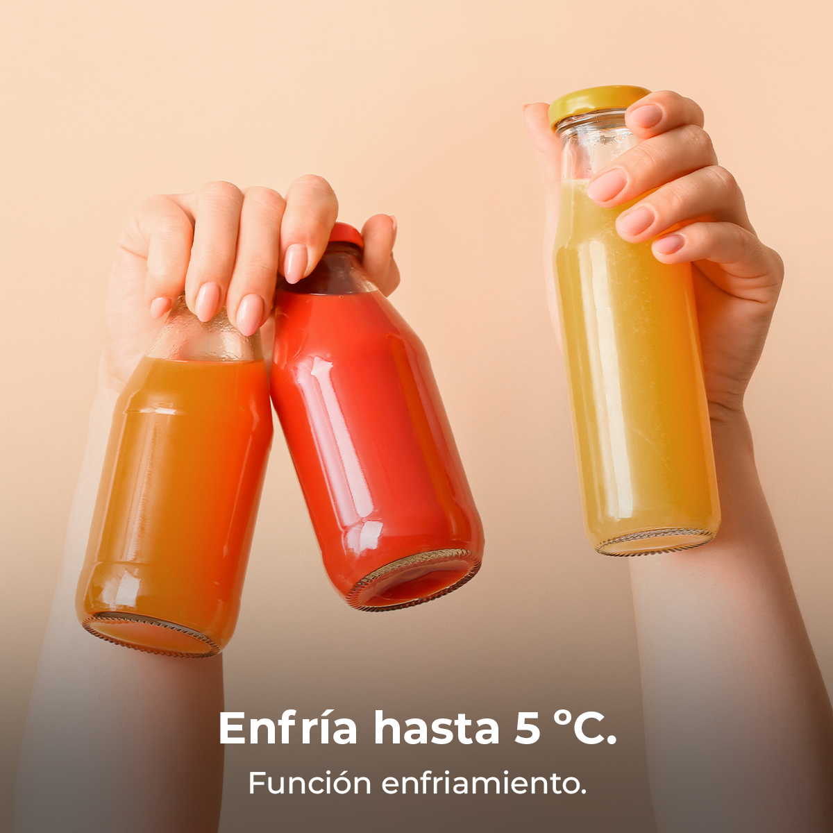 Dłonie trzymające trzy szklane butelki wypełnione pomarańczowym, czerwonym i żółtym sokiem. Tło jest jednolite w kolorze brzoskwiniowym.