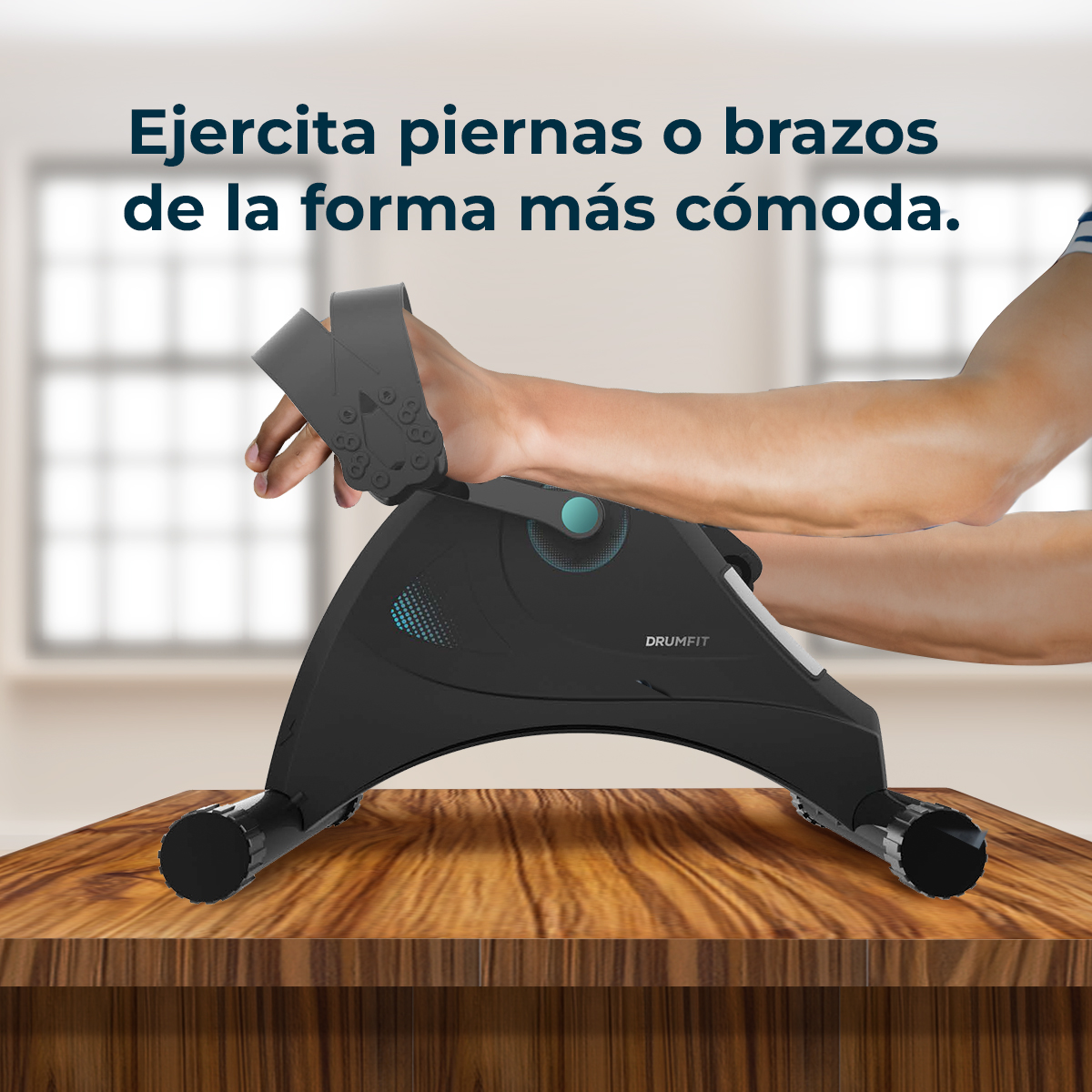 Osoba używa czarnej maszyny do ćwiczeń Drumfit ręką. Maszyna stoi na drewnianym stole, a w tle widać okno.