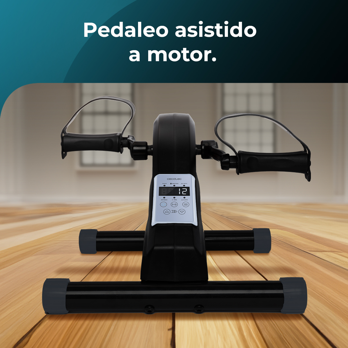 Czarny rower treningowy z cyfrowym wyświetlaczem na drewnianej podłodze, tekst powyżej to 'Pedaleo asistido a motor'.