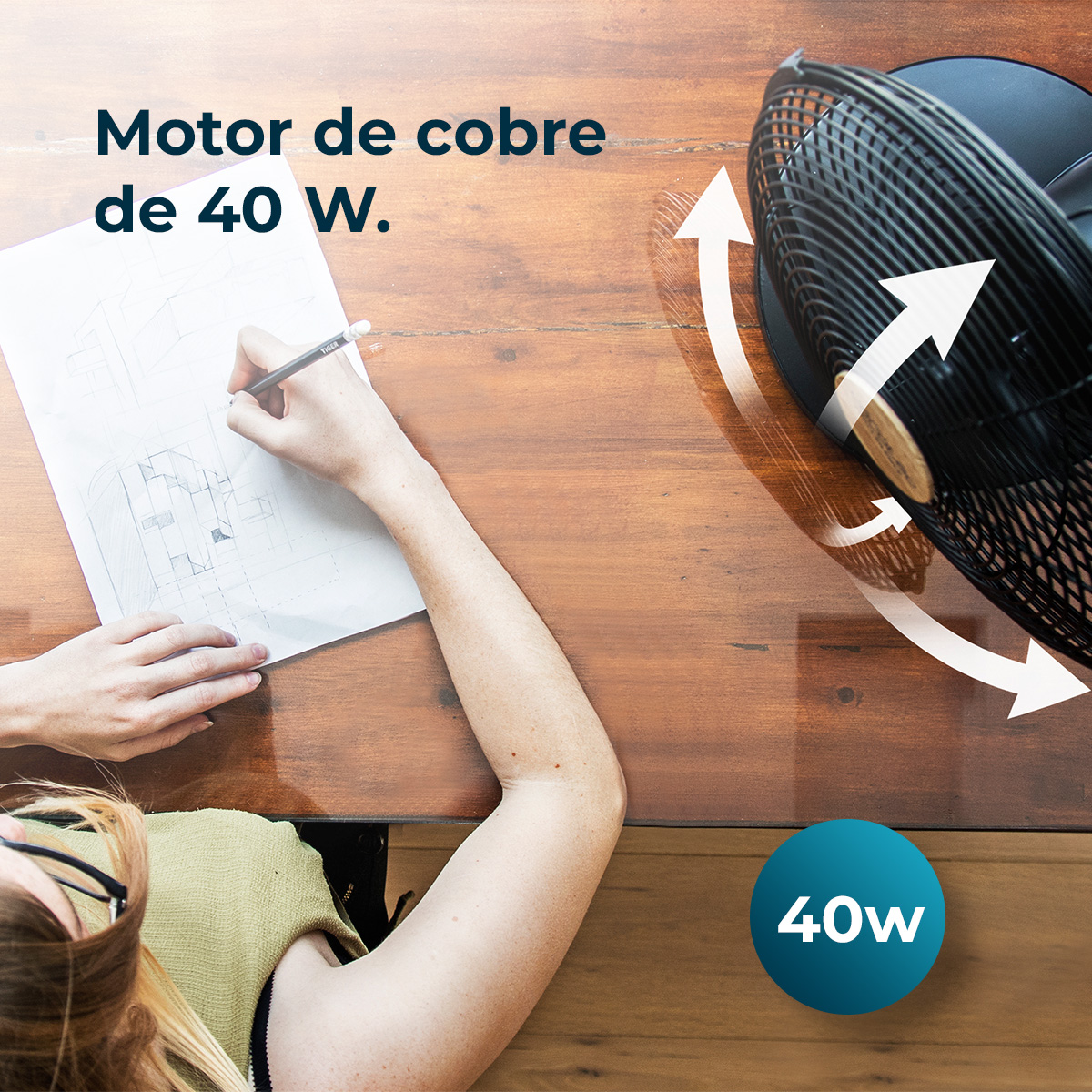 Osoba rysuje na papierze ołówkiem. Czarny wentylator jest w rogu. Tekst mówi silnik miedziany 40 W. Znak 40w znajduje się na dole.