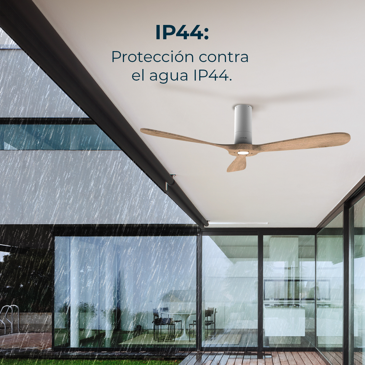 Nowoczesny wentylator sufitowy zewnętrzny z drewnianymi łopatkami, pod białym sufitem. Deszcz pada na zewnątrz szklanych ścian nowoczesnego domu.