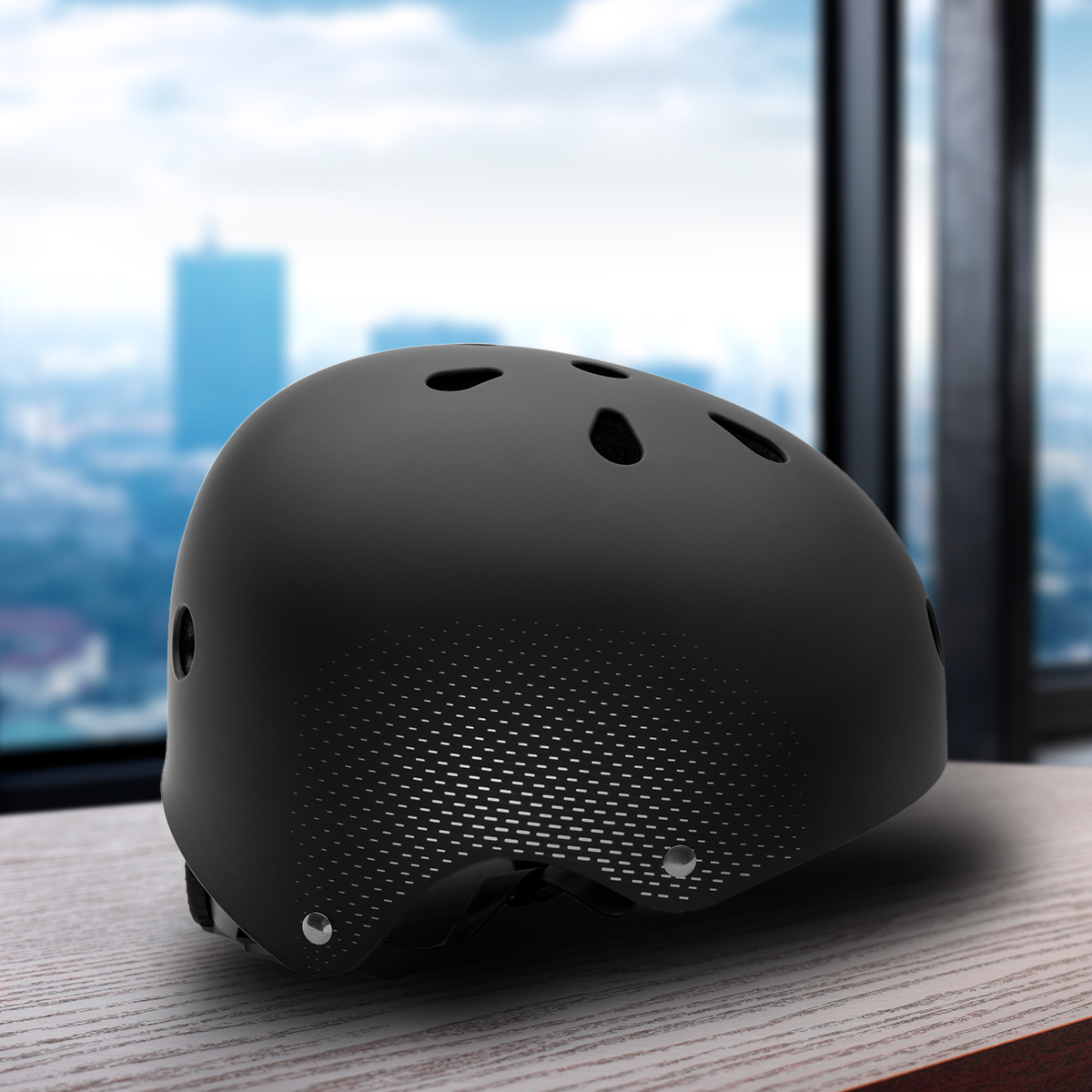 Un casco negro con ventilaciones está sobre una mesa de madera. Una ciudad con edificios altos es visible en el fondo.