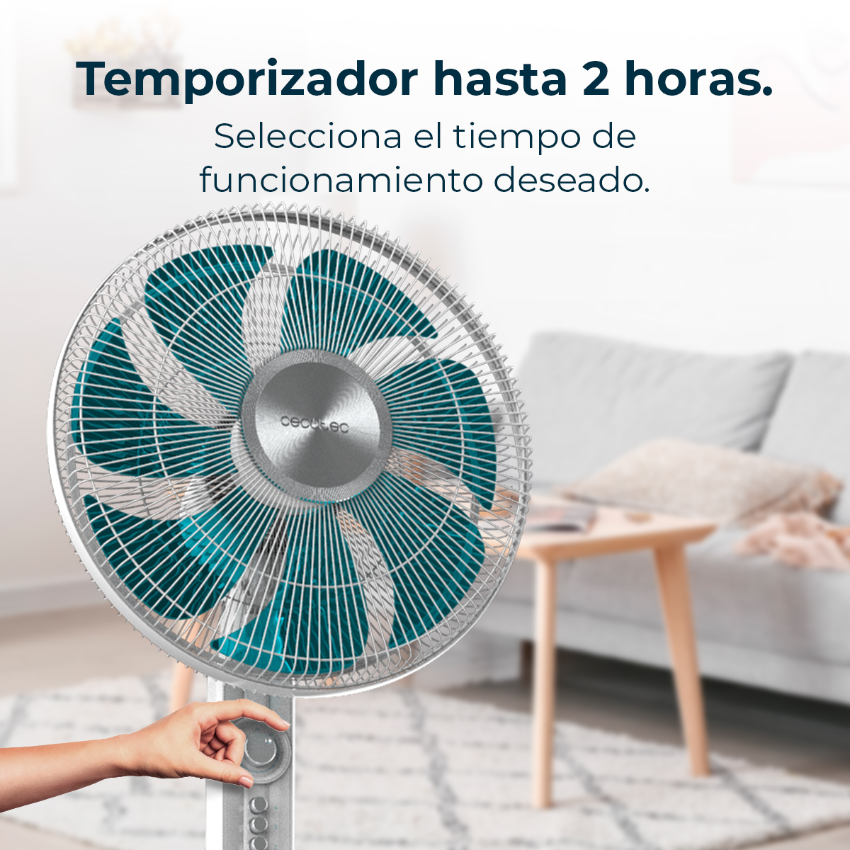 Ein Ventilator mit teal-farbenen Blättern vor verschwommenem Wohnzimmer. Eine Hand stellt die Einstellungen ein. Spanischer Text oben.