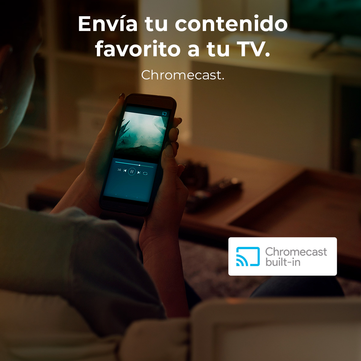 Una persona sostiene un teléfono, transmitiendo contenido a un televisor a través de Chromecast. El teléfono muestra un video con controles.