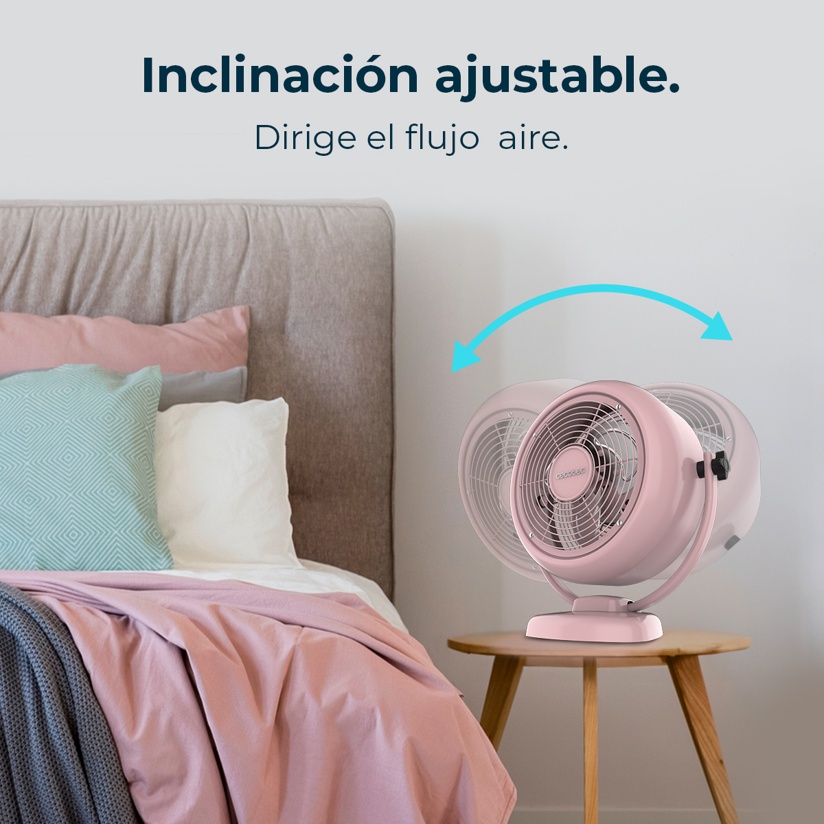 Un ventilatore rosa su un tavolo di legno, accanto a un letto. Il letto ha lenzuola e cuscini rosa e bianchi. Iscrizione: 'Inclinazione regolabile'.