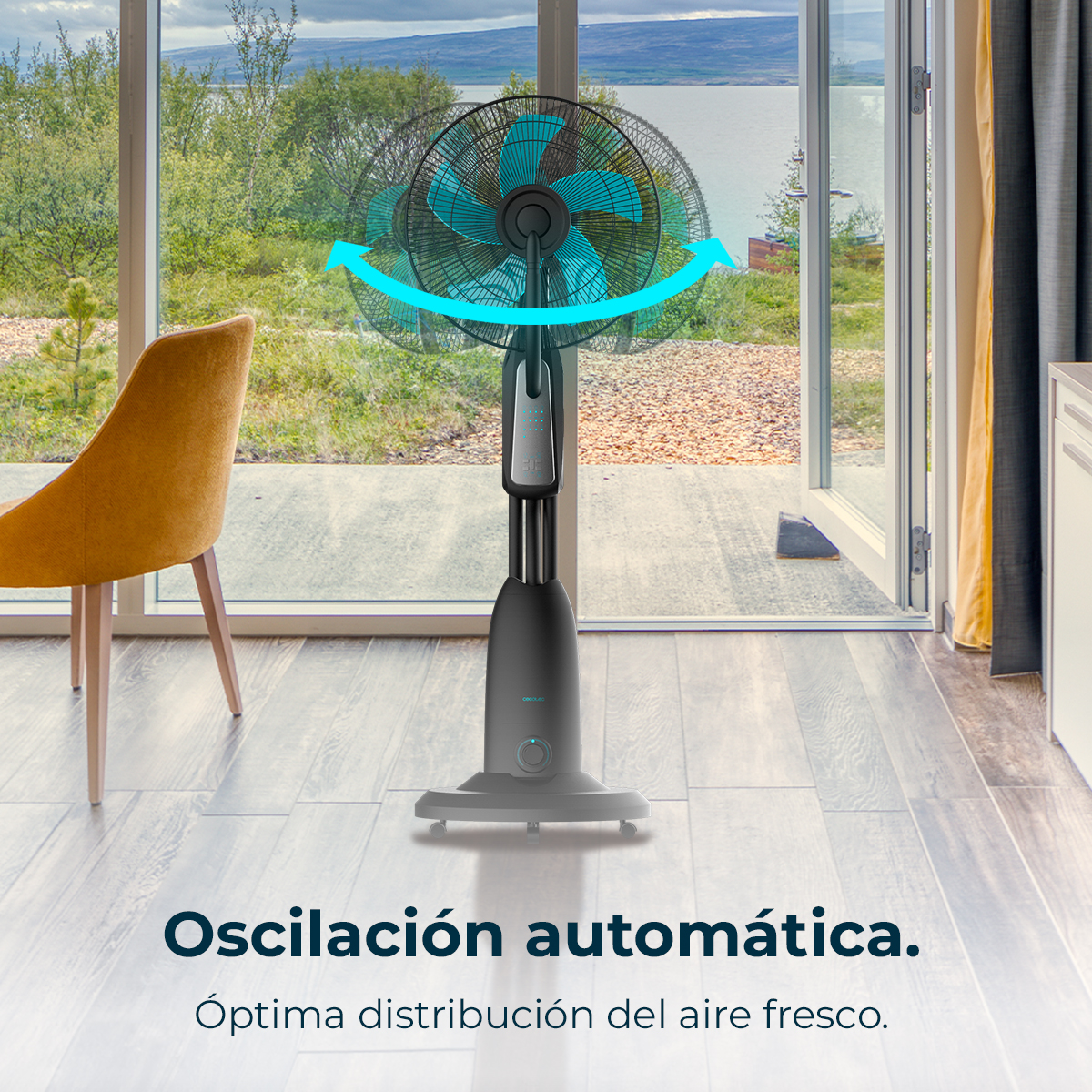 Un ventilador oscilante negro con aspas azules está en una habitación. Una ventana muestra un lago y montañas. Una silla amarilla a la izquierda.