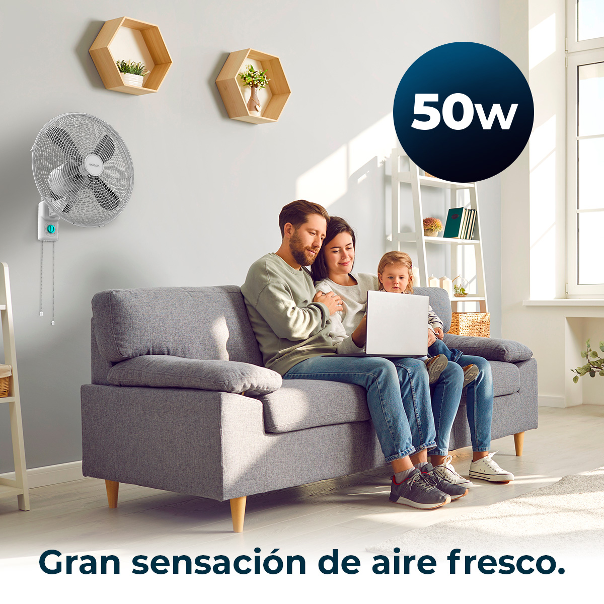 Una familia sentada en un sofá, usando una laptop. Un ventilador está en la pared. El texto 'Gran sensación de aire fresco' está debajo.