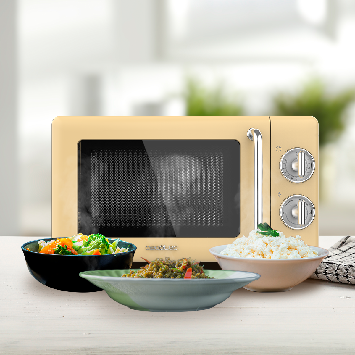 Beżowa kuchenka mikrofalowa z pokrętłami i uchwytem. Przed nią miski z jedzeniem. Tło jest rozmyte.