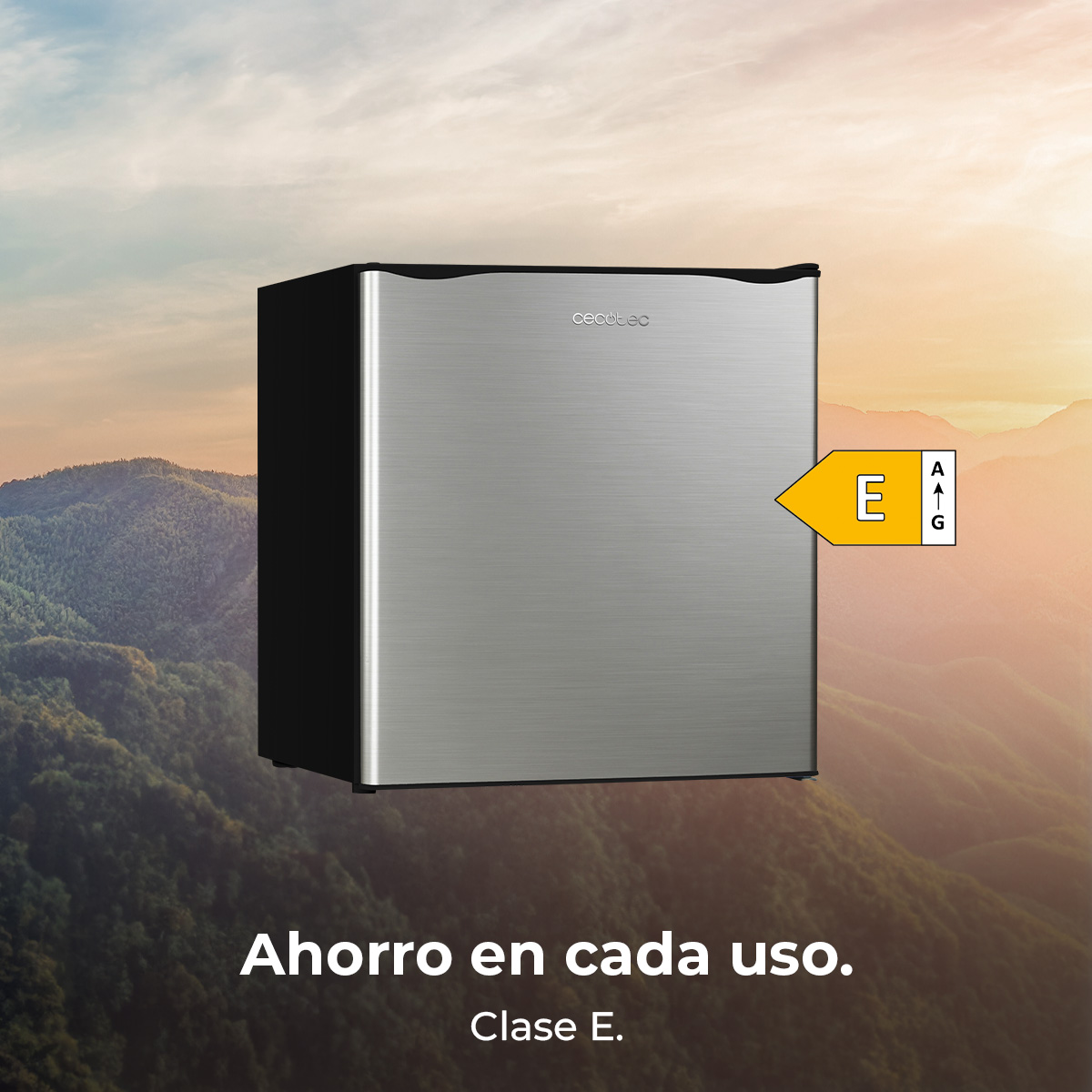 Srebrna lodówka z czarnym bokiem stoi na tle gór. Etykieta energetyczna pokazuje ocenę E. Tekst: ahorro en cada uso.