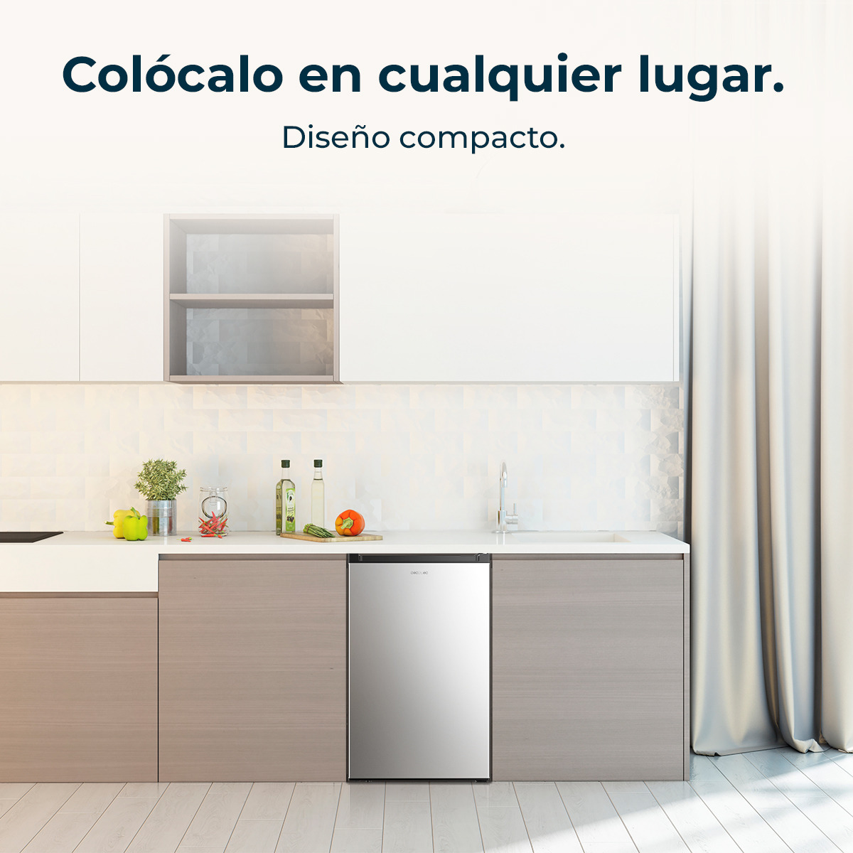 Escena de cocina con un frigorífico pequeño. Encimera con comestibles. Armarios y pared de azulejos al fondo. Texto: Colócalo en cualquier lugar.