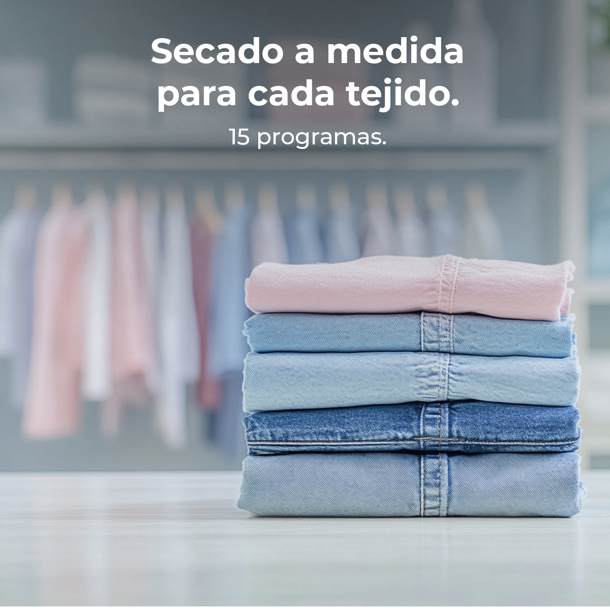 Una pila de ropa vaquera doblada: rosa, azul claro y azul oscuro. El fondo muestra ropa colgando y texto en español.